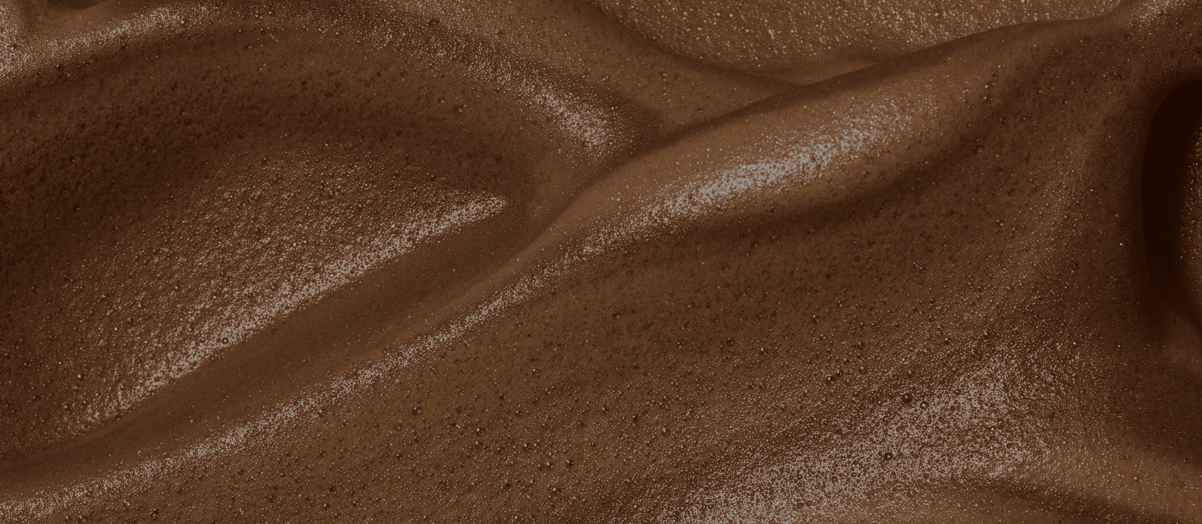 Close-up macro shot of the rich, velvety bronze texture of Peta Jane Beauty Tanning Mousse.