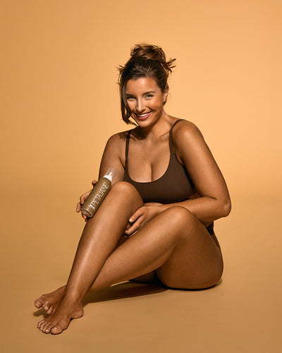 Model sitting with dark mousse bottle in hand smiling