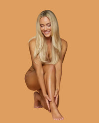 peta Murgatroyd sitting smiling after self tanning holding one leg
